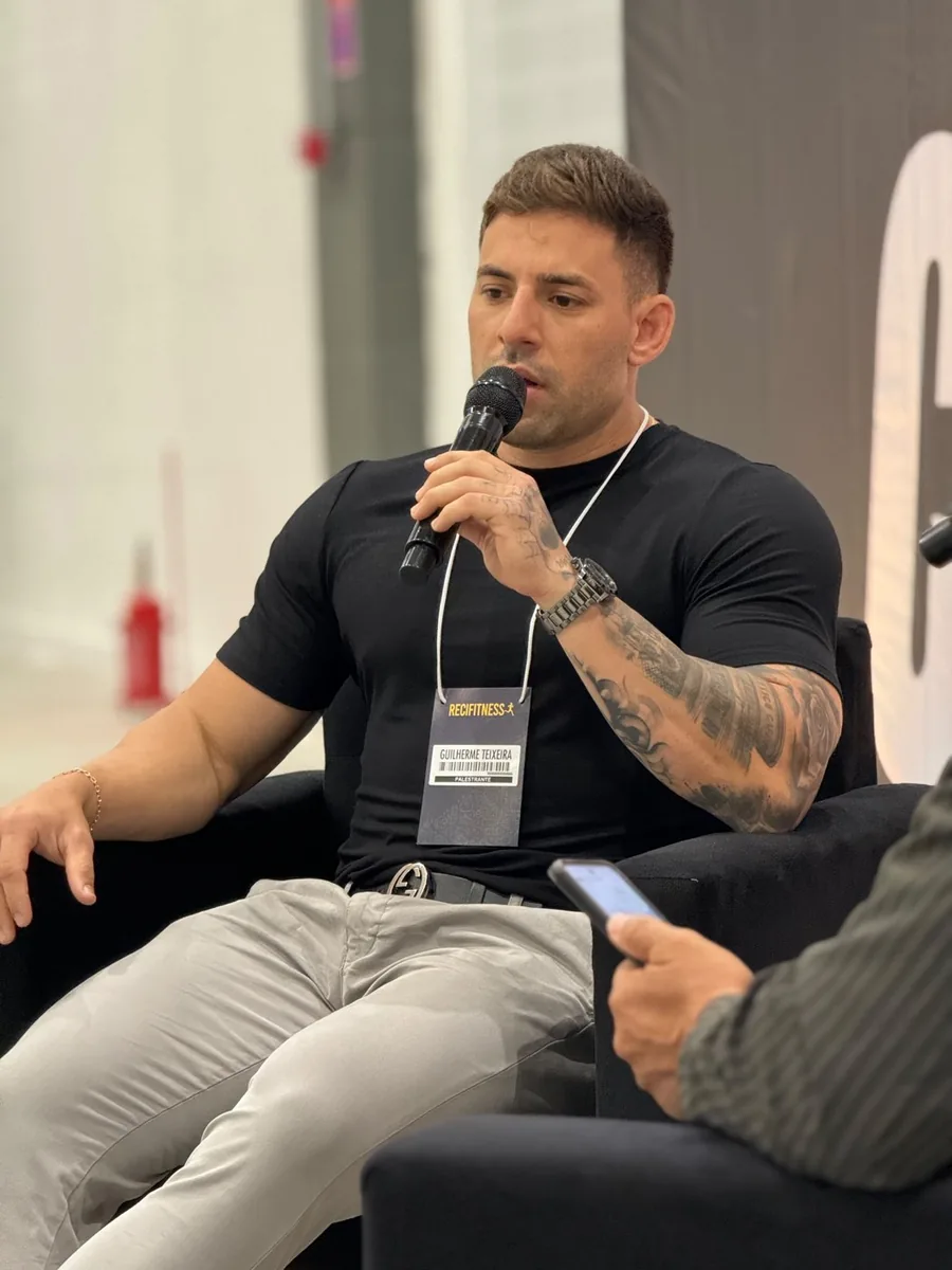 Gui Teixeira ao microfone, com crachá de palestrante do Recifitness